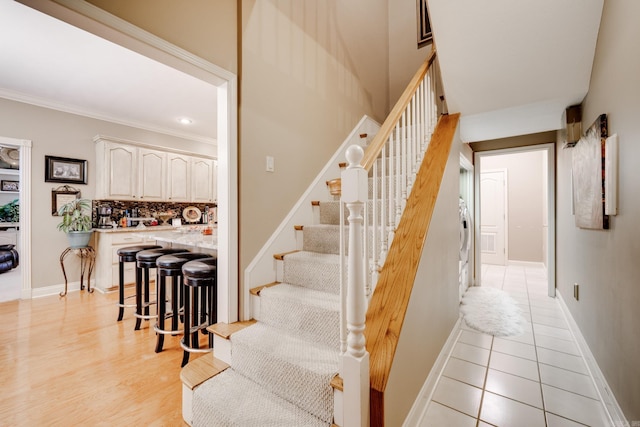 stairs with crown molding and light tile flooring