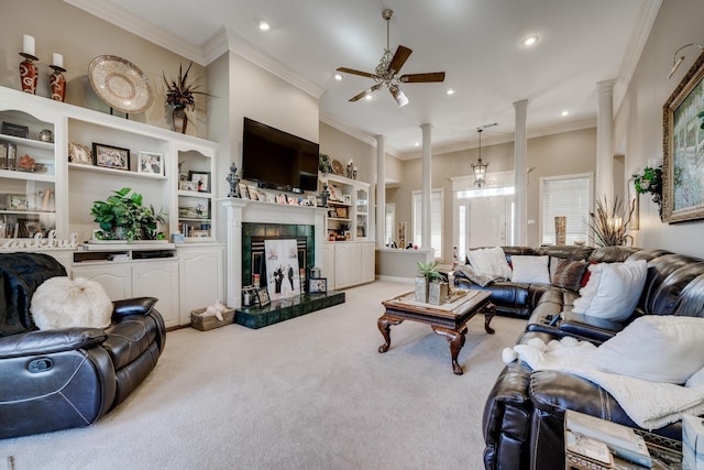 carpeted living room featuring a tiled fireplace, ceiling fan, built in shelves, and crown molding