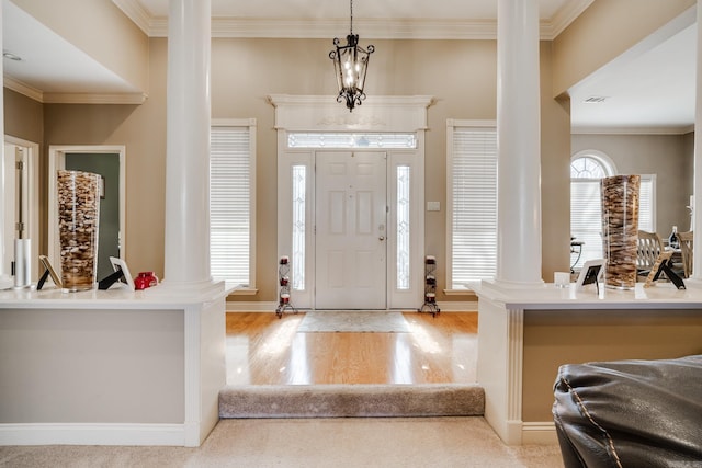 foyer featuring ornate columns, a healthy amount of sunlight, and light wood-type flooring