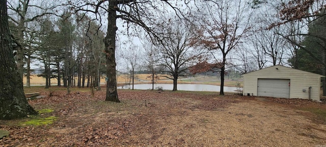 view of yard featuring an outbuilding, a water view, a detached garage, and dirt driveway