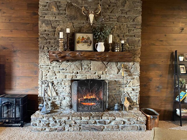 interior details featuring carpet floors, a stone fireplace, and a wood stove