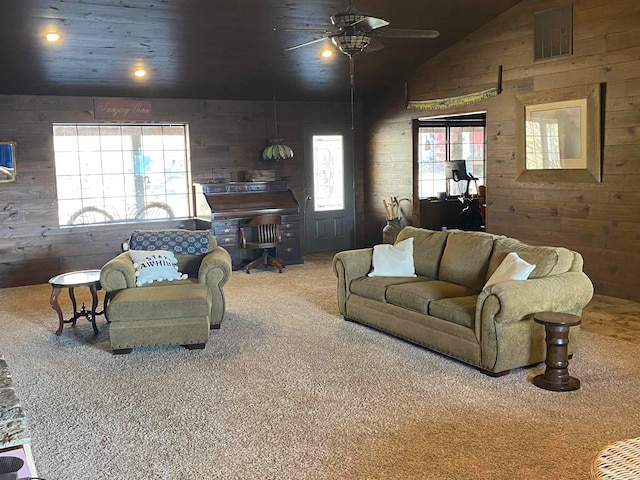 living room featuring lofted ceiling, wooden walls, carpet flooring, and ceiling fan