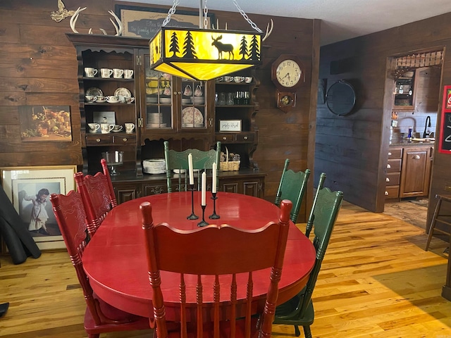 dining area featuring wood walls, sink, and light hardwood / wood-style flooring