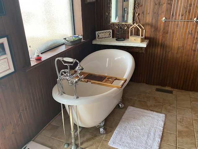 bathroom with tile floors, wooden walls, and a washtub