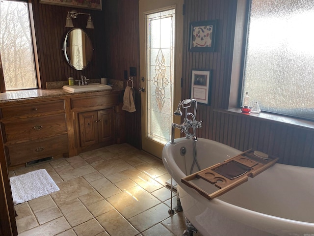 bathroom with tile flooring, a bathing tub, and vanity