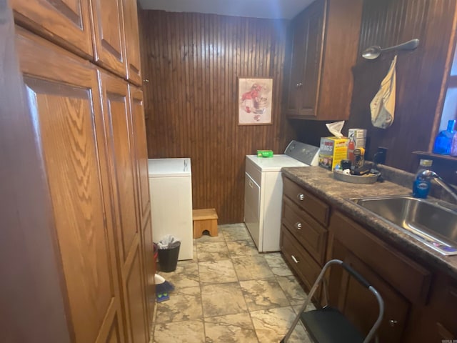 washroom featuring cabinets, sink, light tile floors, wood walls, and independent washer and dryer