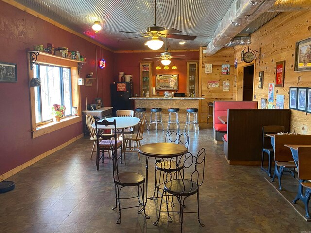 dining area with wooden walls, dark tile flooring, and ceiling fan