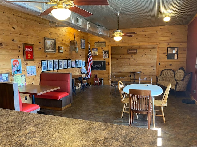 dining room with ceiling fan and wooden walls