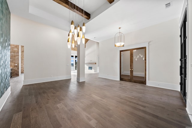 unfurnished living room with dark wood-style floors, beamed ceiling, visible vents, and baseboards