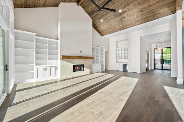 unfurnished living room featuring dark wood finished floors, high vaulted ceiling, a glass covered fireplace, and wood ceiling