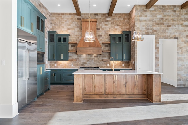 kitchen featuring dark wood finished floors, light countertops, a sink, and built in appliances