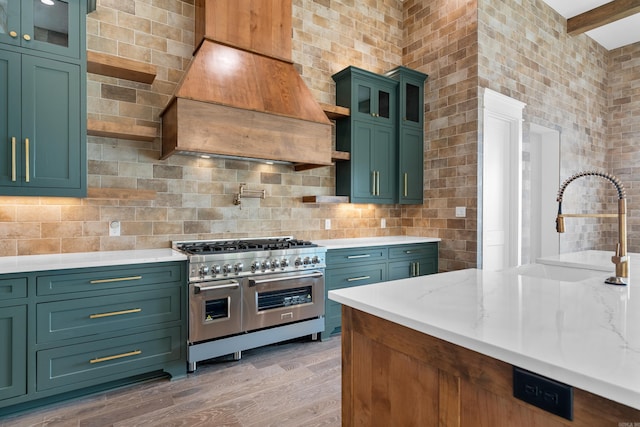 kitchen featuring range with two ovens, green cabinetry, a sink, light wood-style floors, and custom range hood