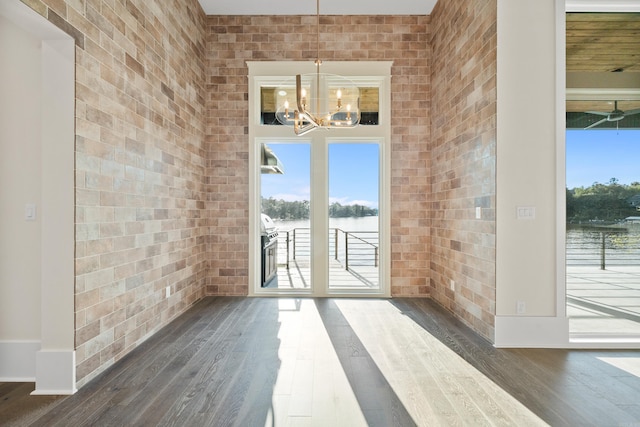 doorway featuring dark wood-type flooring, a wealth of natural light, and brick wall