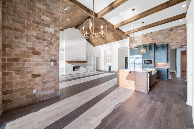 kitchen featuring dark wood-type flooring, a lit fireplace, light countertops, blue cabinetry, and high vaulted ceiling