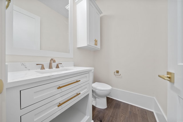 bathroom with baseboards, vanity, toilet, and wood finished floors