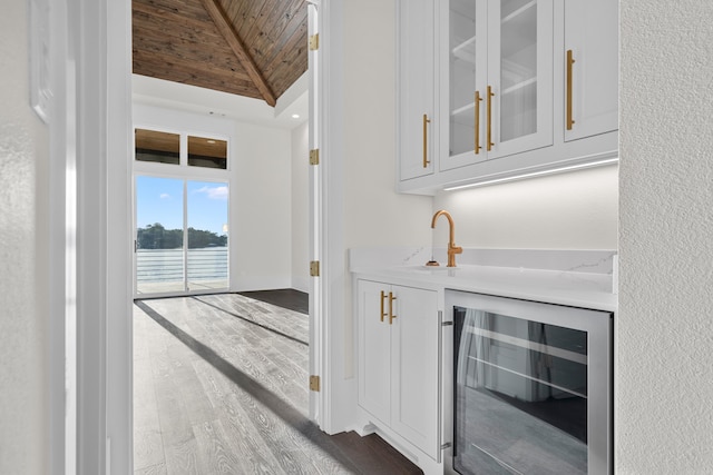 bar with wine cooler, lofted ceiling with beams, a sink, wood finished floors, and wooden ceiling