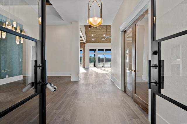 entryway with french doors, a high ceiling, baseboards, and wood finished floors