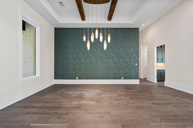 unfurnished room featuring dark wood finished floors, visible vents, an accent wall, beamed ceiling, and baseboards