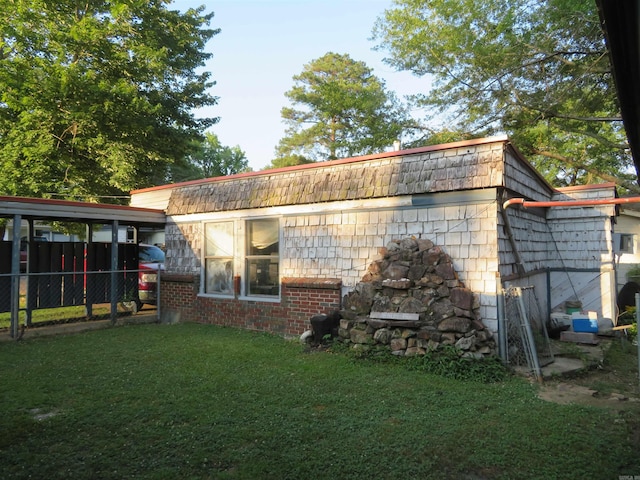 back of property with a carport and a yard