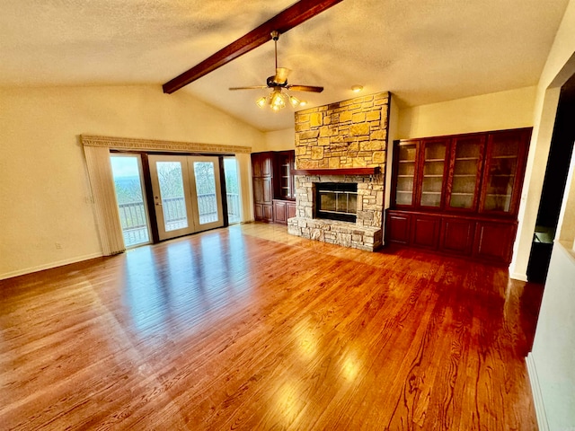 unfurnished living room featuring a fireplace, ceiling fan, vaulted ceiling with beams, and hardwood / wood-style flooring