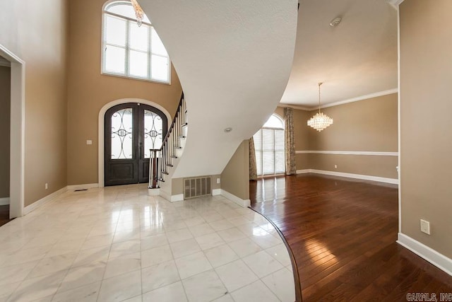 entryway with an inviting chandelier, plenty of natural light, light hardwood / wood-style floors, and ornamental molding