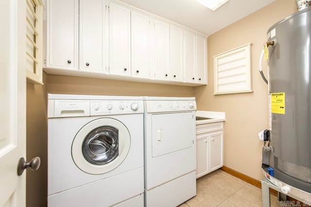 clothes washing area with cabinets, light tile flooring, and washer and dryer