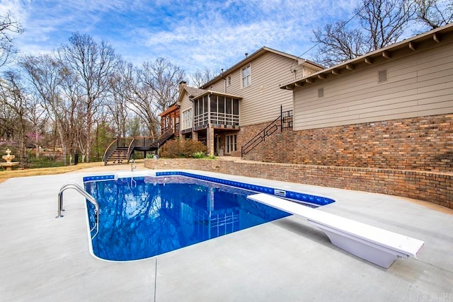 view of pool with a patio area and a diving board