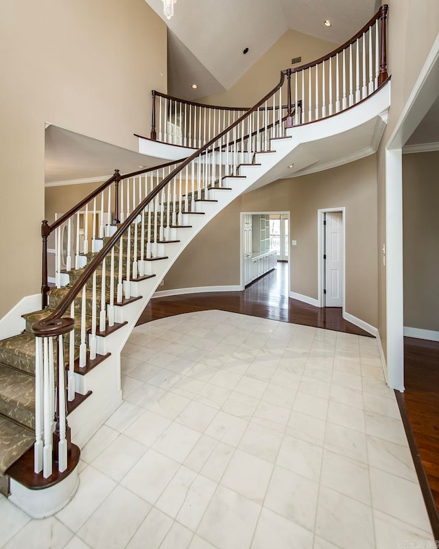 stairs with ornamental molding, light wood-type flooring, and a high ceiling