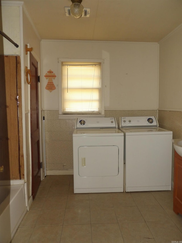 laundry room with washing machine and clothes dryer, crown molding, and light tile floors