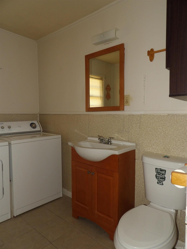 bathroom featuring tile floors, toilet, washing machine and dryer, and vanity