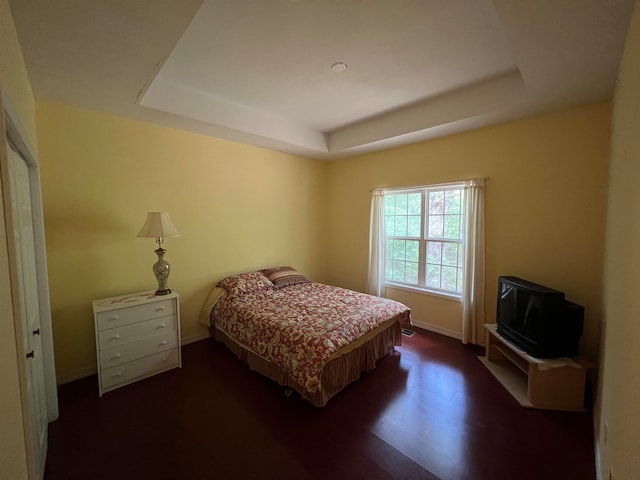 bedroom featuring dark hardwood / wood-style flooring and a tray ceiling