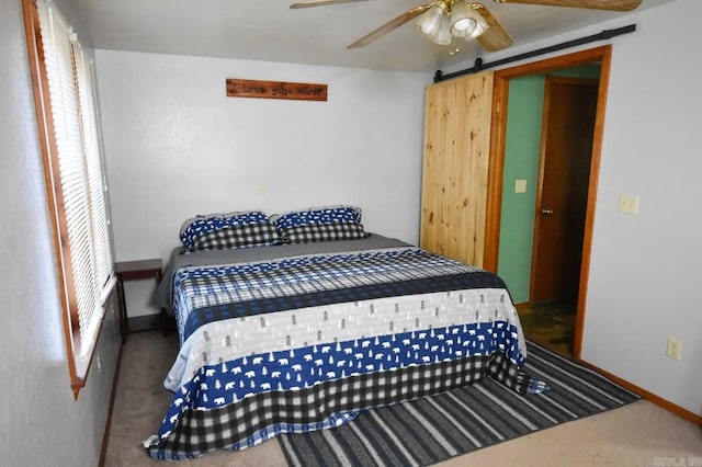 bedroom featuring ceiling fan, multiple windows, carpet flooring, and a barn door