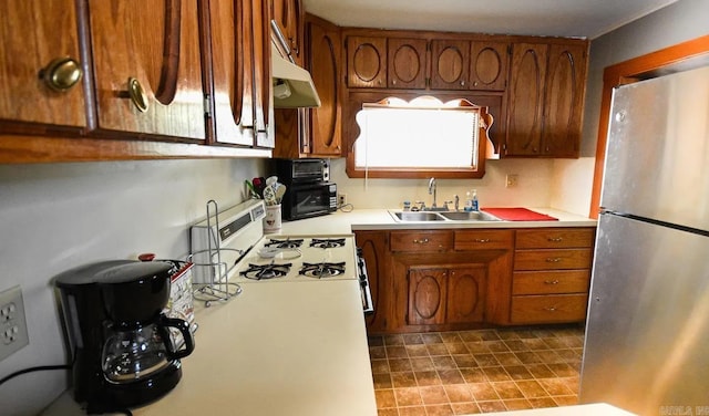 kitchen featuring stainless steel refrigerator, sink, and white range oven