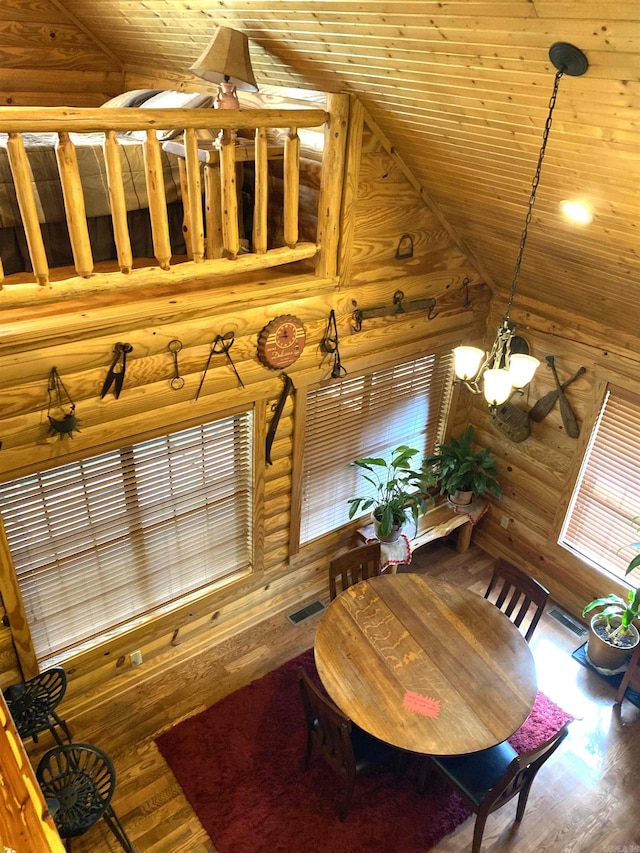 interior space with rustic walls, an inviting chandelier, wood-type flooring, and lofted ceiling