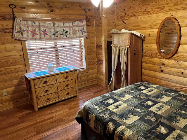 bedroom with log walls and dark hardwood / wood-style flooring