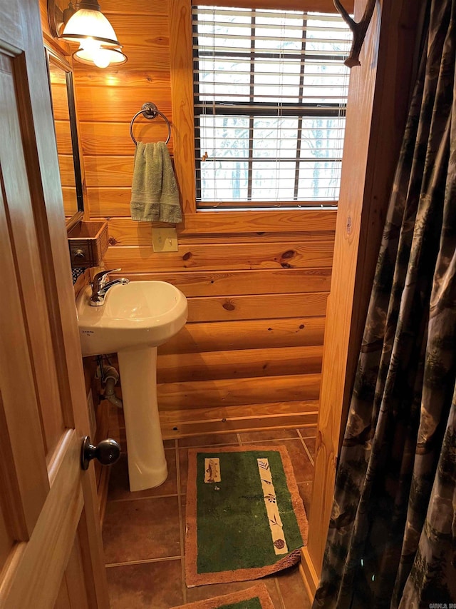 bathroom with wood walls and tile flooring