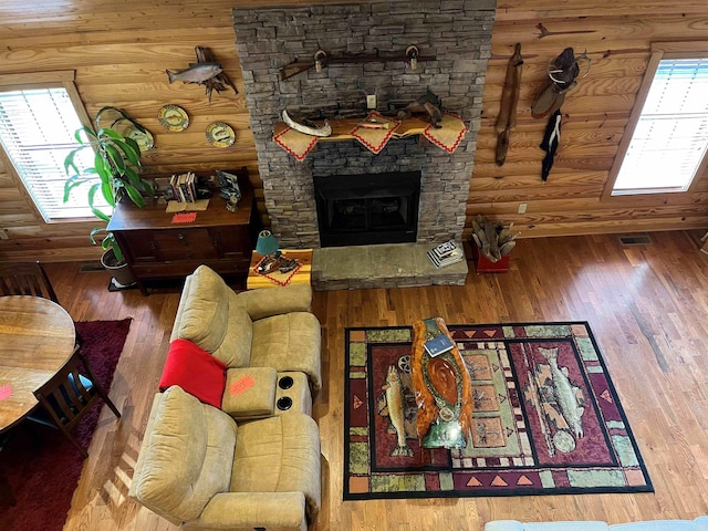 living room featuring log walls, wood-type flooring, and a stone fireplace