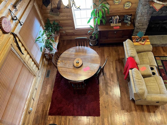 dining room featuring a fireplace, hardwood / wood-style floors, a notable chandelier, and rustic walls