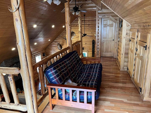 interior space with ceiling fan, wood ceiling, light hardwood / wood-style flooring, rustic walls, and lofted ceiling