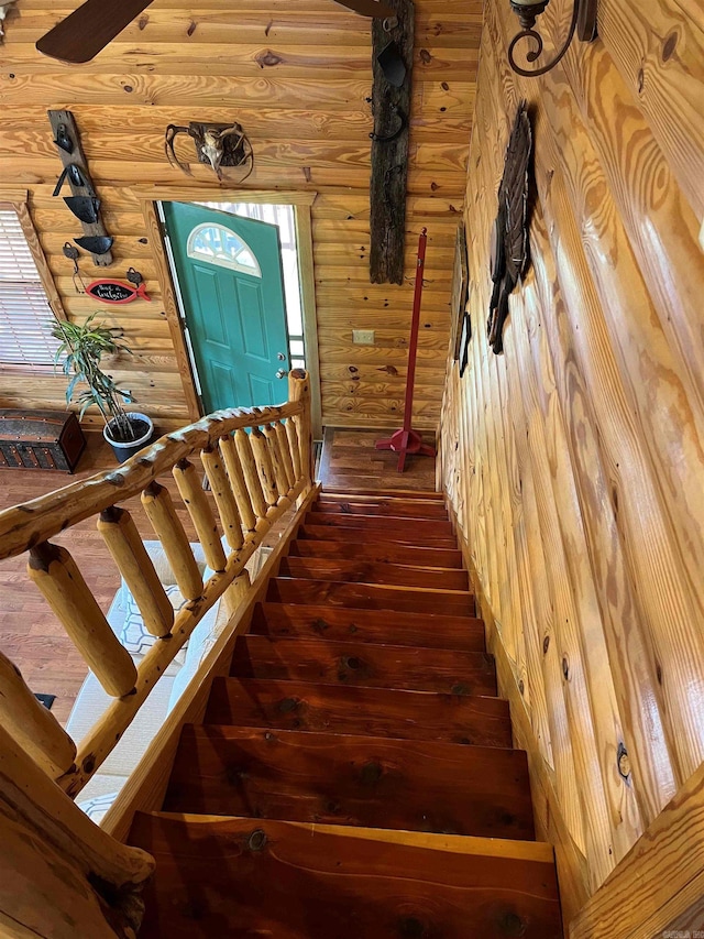 staircase with log walls and dark hardwood / wood-style floors