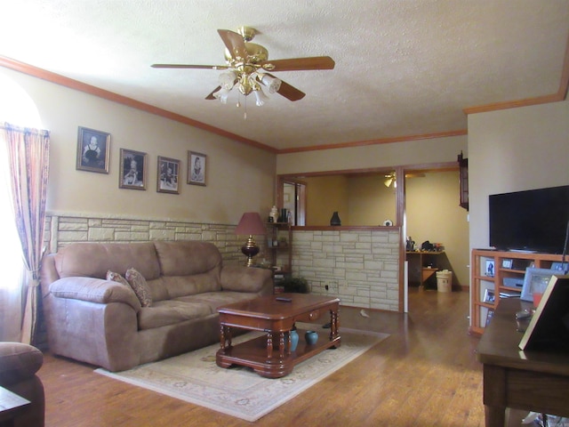 living room with a textured ceiling, ceiling fan, hardwood / wood-style flooring, and crown molding