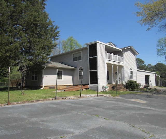 view of front facade featuring a balcony and a front lawn