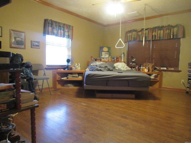 bedroom with crown molding, wood-type flooring, and ceiling fan