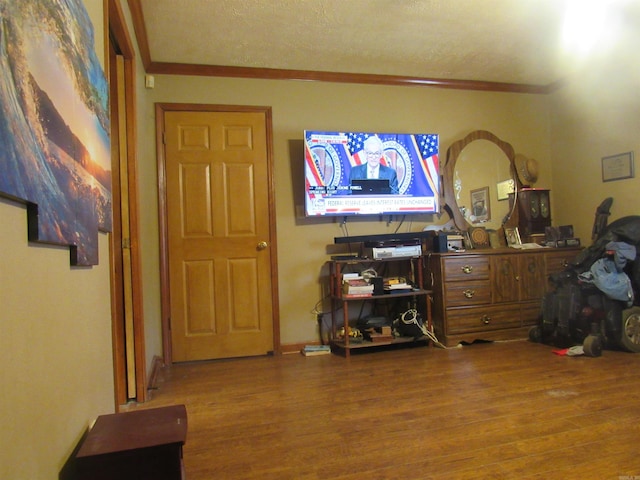 interior space featuring ornamental molding, hardwood / wood-style floors, and a textured ceiling