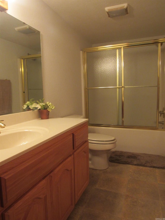 full bathroom with enclosed tub / shower combo, toilet, large vanity, and tile floors