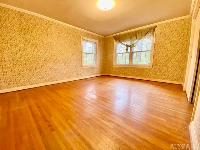 spare room with crown molding, light hardwood / wood-style floors, and a healthy amount of sunlight