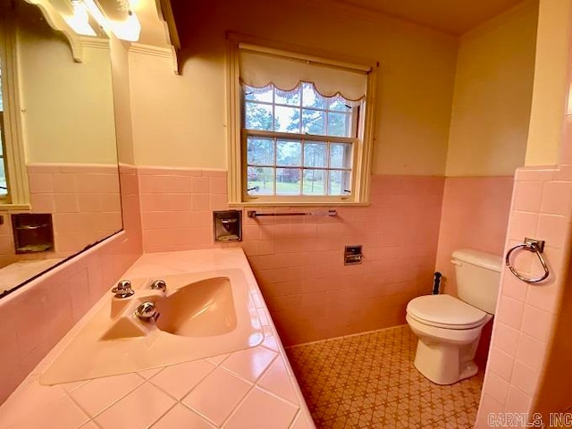 bathroom with tile walls, tile floors, toilet, and sink