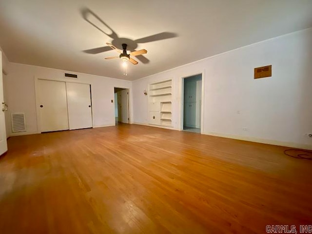 empty room featuring light hardwood / wood-style flooring, ceiling fan, and built in shelves