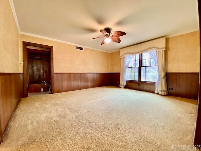 spare room featuring ceiling fan, ornamental molding, and light carpet