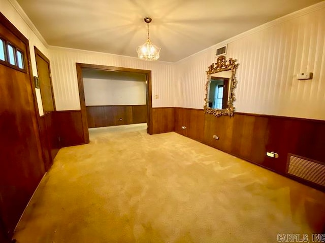 carpeted spare room with an inviting chandelier and crown molding